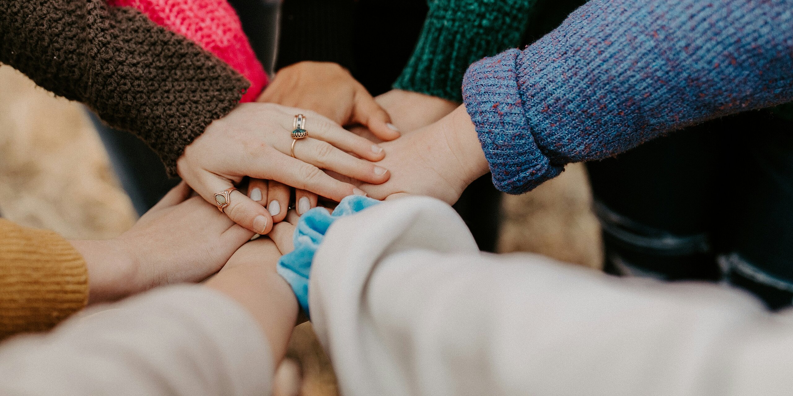 Mehrere Hände liegen aufeinander und suggerieren Zusammenhalt.