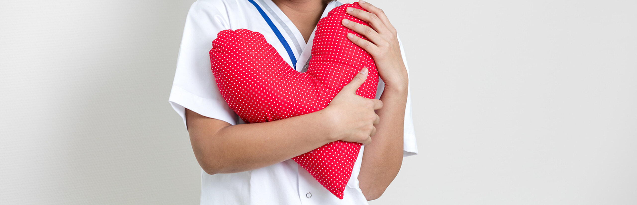 Eine Pflegerin hält ein rotes Herzkissen in der Hand.