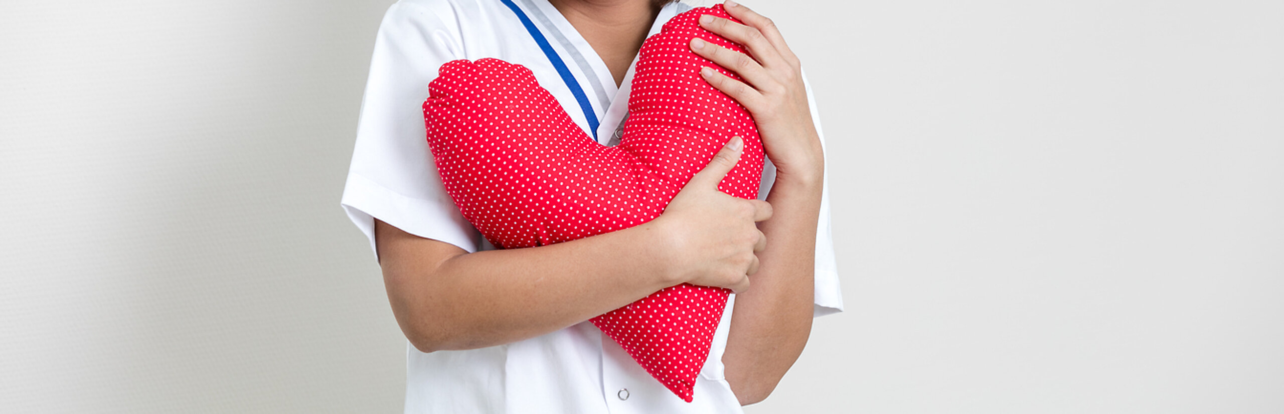 Eine Pflegerin hält ein rotes Herzkissen in der Hand.