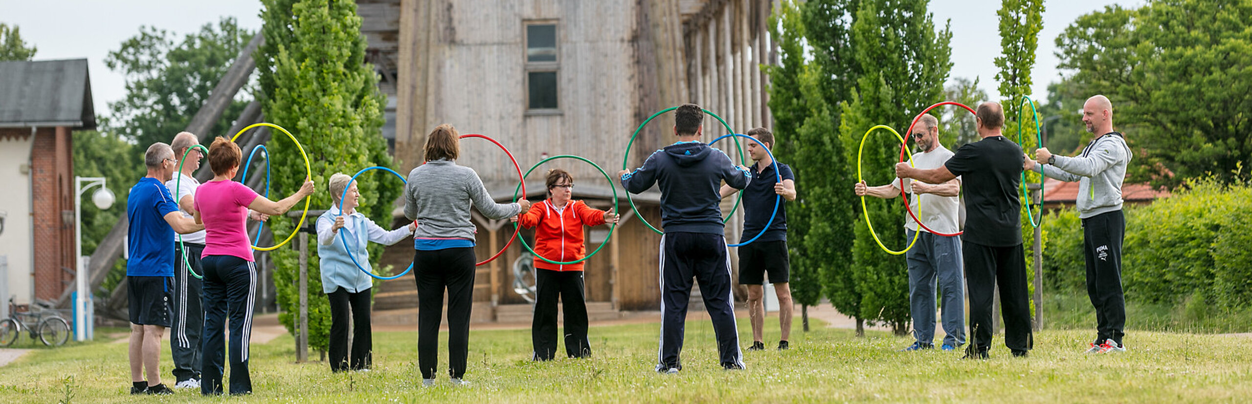 Eine Menschengruppe trainiert vor dem Gradierwerk Bad Salzelmen mit Reifen in den Händen.