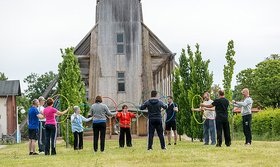 Eine Menschengruppe trainiert vor dem Gradierwerk Bad Salzelmen mit Reifen in den Händen.