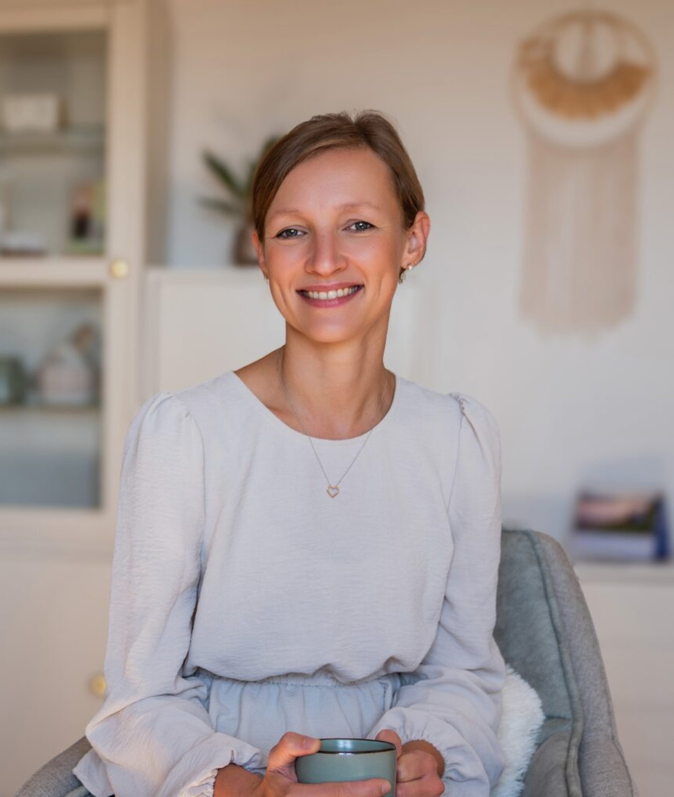 Monika Resch sitzt lächelnd in ihrer Praxis.