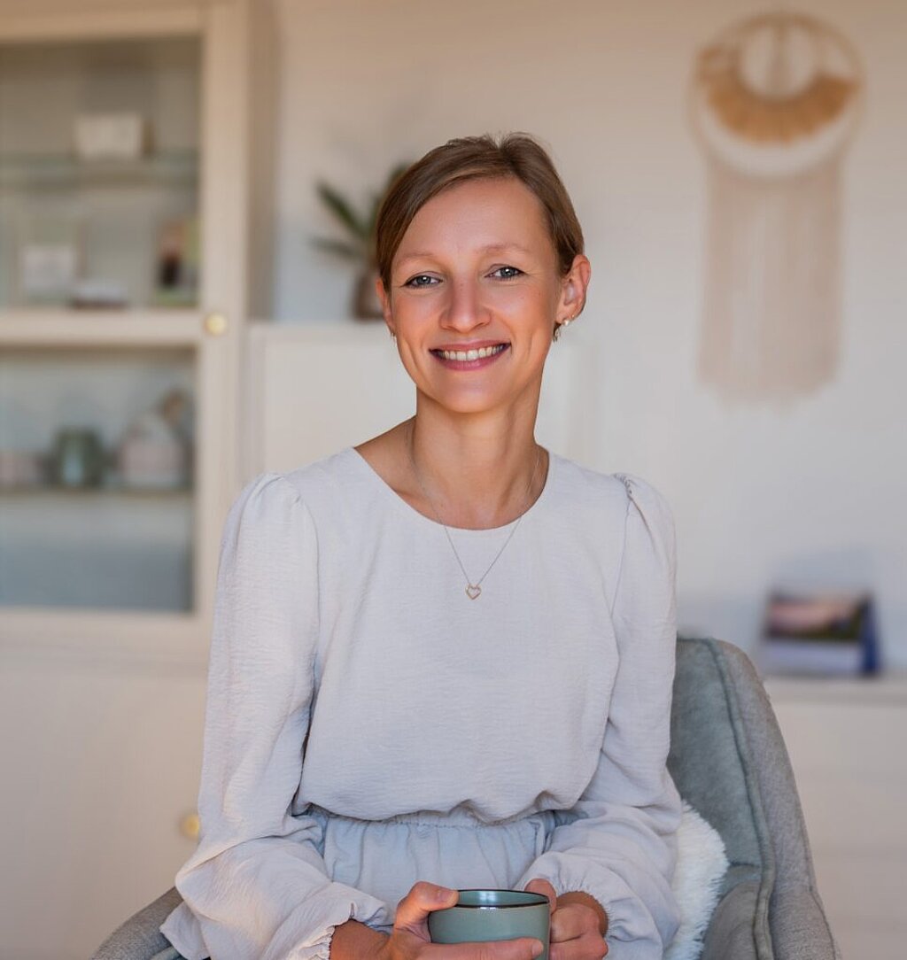 Monika Resch sitzt lächelnd in ihrer Praxis.