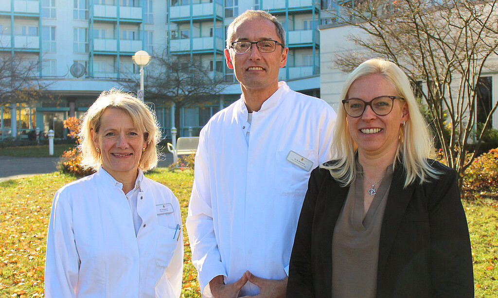 Die Klinikleitung - bestehend aus der orthopädischen Chefärztin, dem onkologischen Chefarzt sowie der kaufmännischen Leiterin - lächeln in die Kamera.
