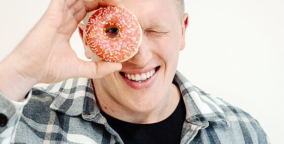 Jan Blaschko sieht mit einem Auge durch einen Donut.