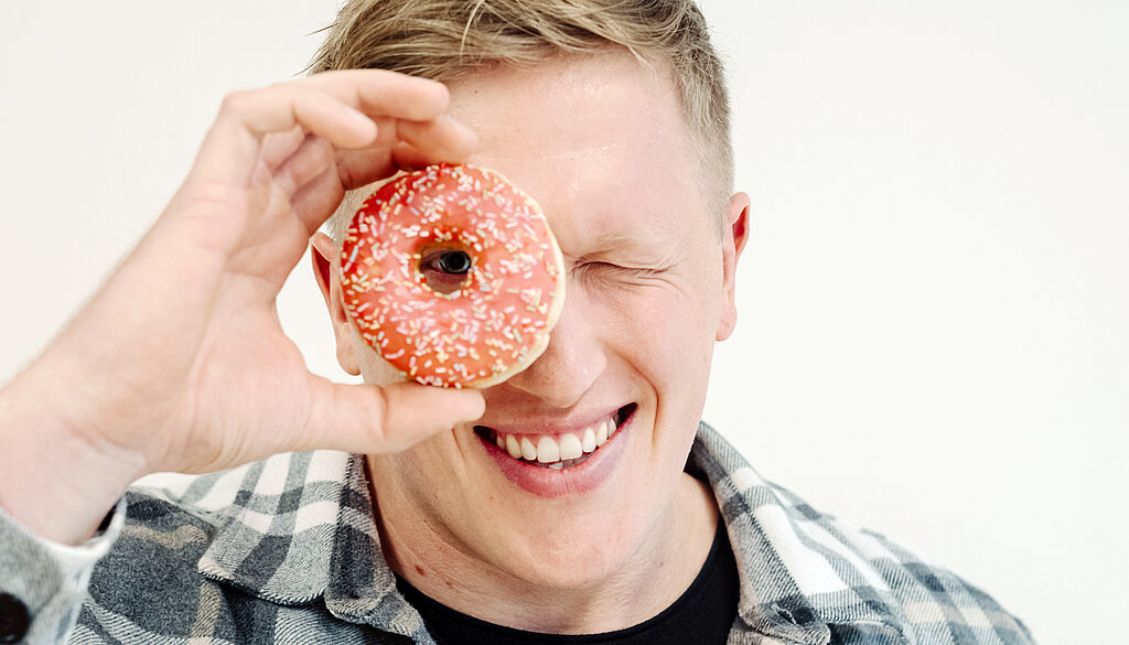 Jan Blaschko sieht mit einem Auge durch einen Donut.