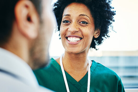 Gespräch Pflegerin Eine lächelnde Pflegekraft schaut einen Arzt an.