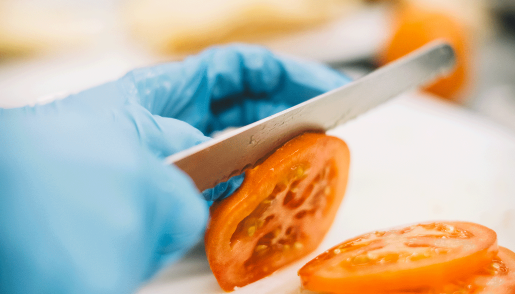 Nahaufnahme vom Schneiden einer Tomate mit einem Messer.