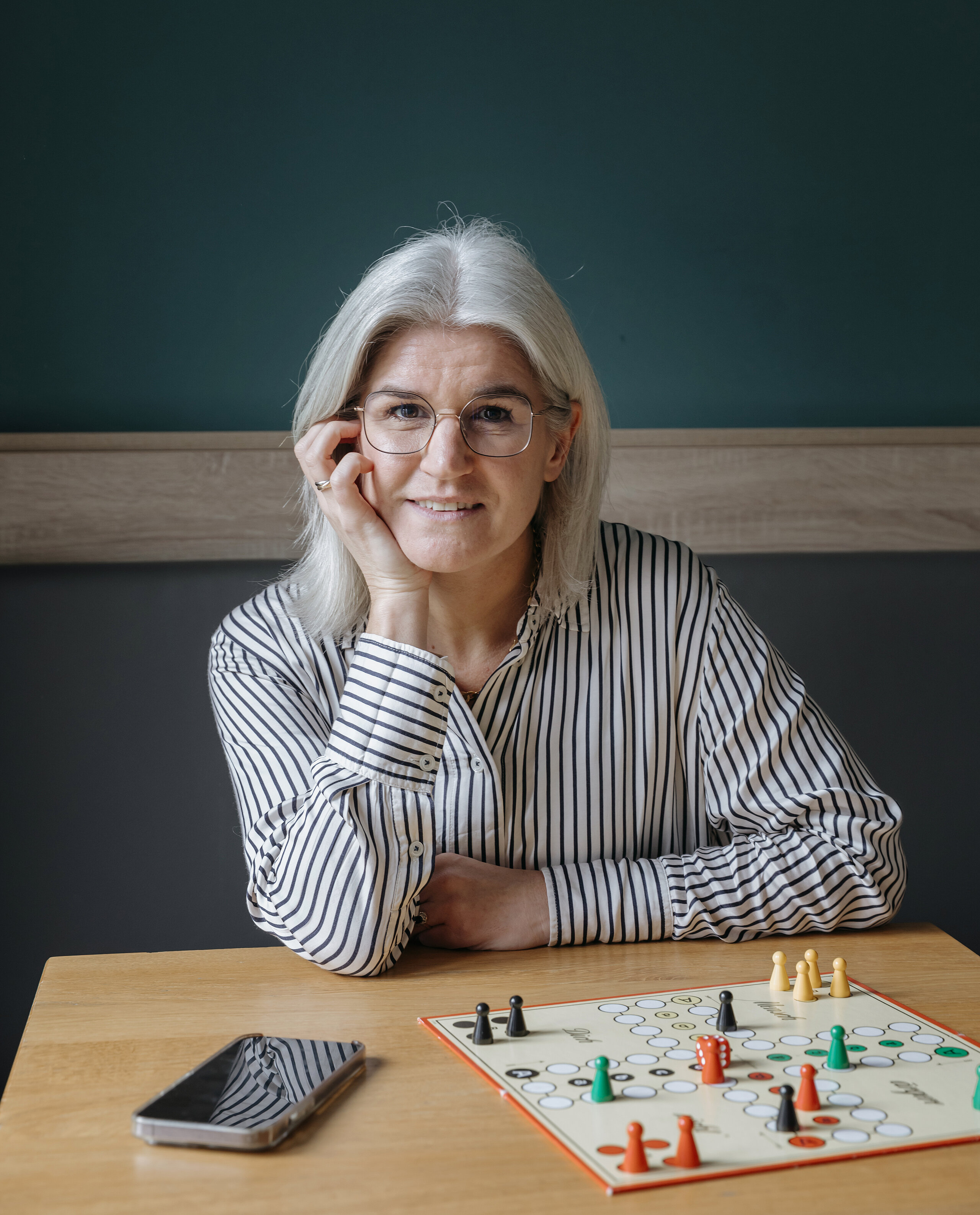 Nora Volmer-Berthele sitzt mit einem Spiel am Tisch.