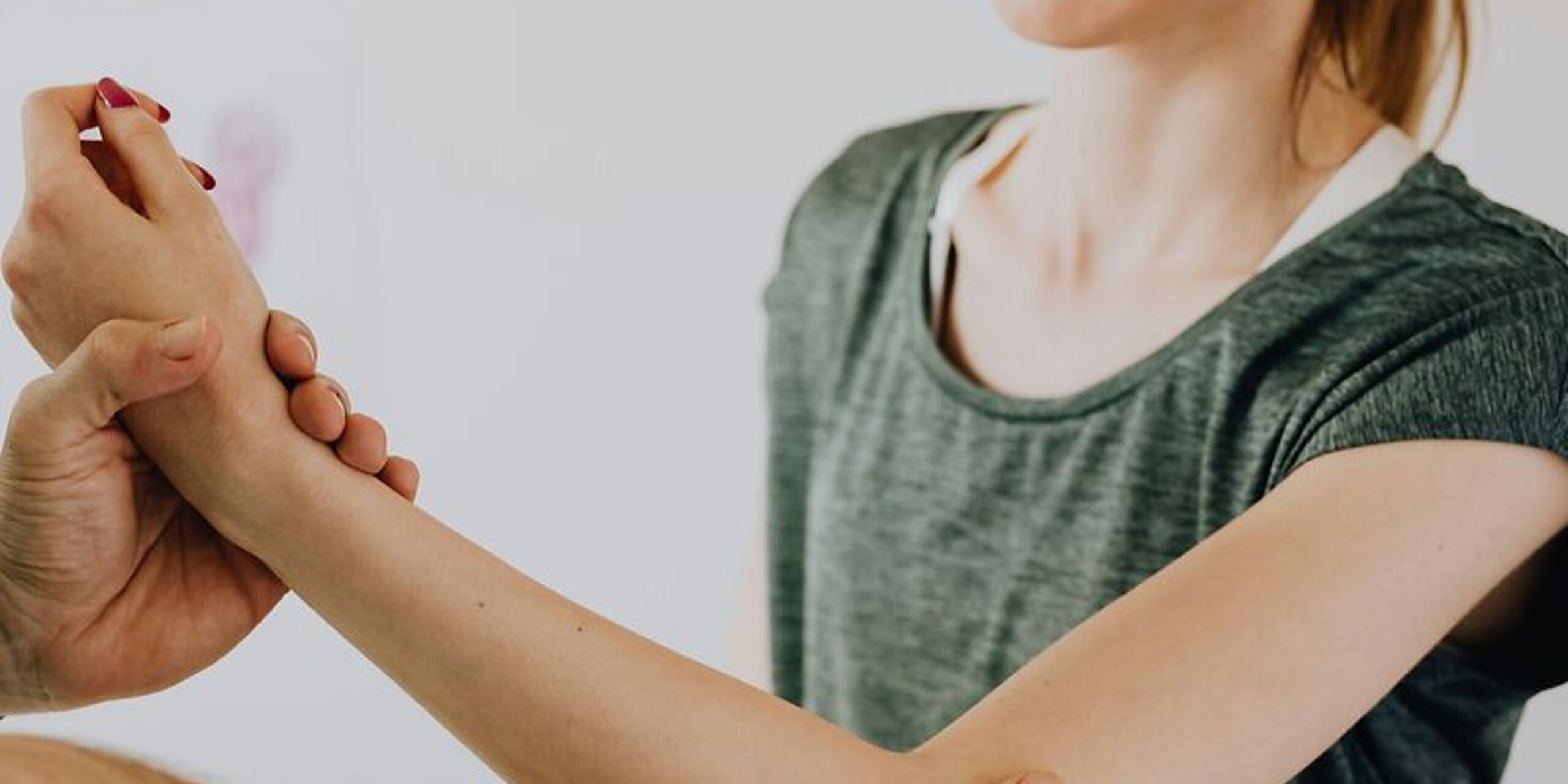 Ein Therapeut behandelt den Ellenbogen einer Patientin.