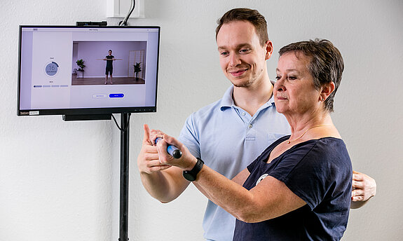 Ein Therapeut weist eine Patientin in die digitale Nachsorge ein