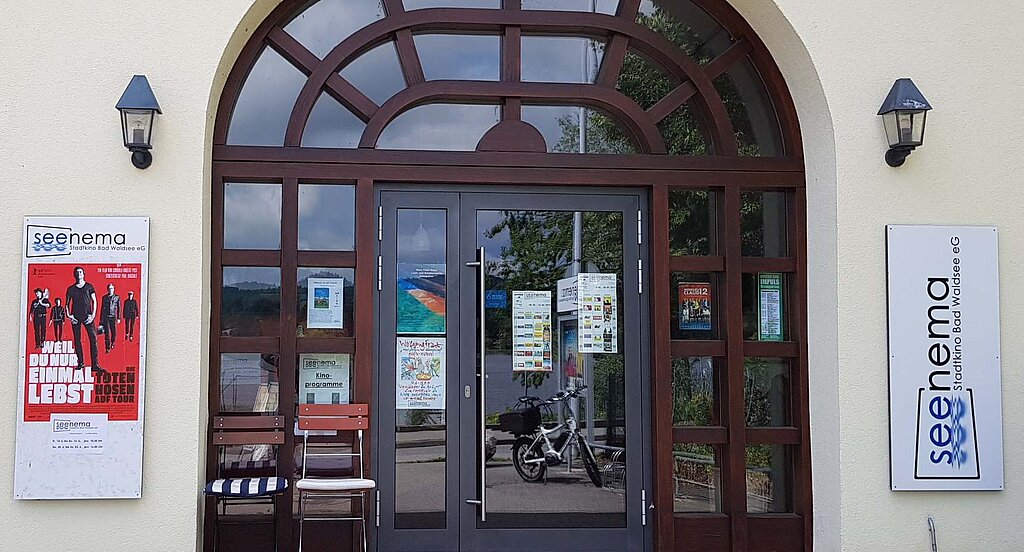 Eingang des Seenema-Kinos in Bad Waldsee mit Plakaten und Leuchtschild an der Fassade.