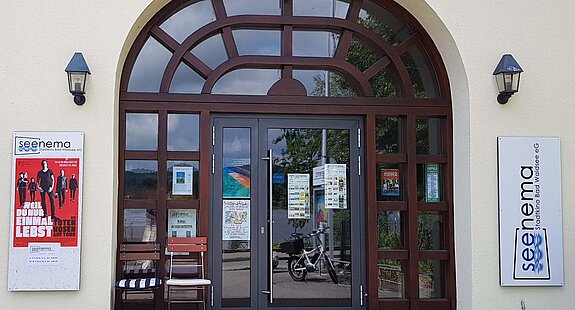 Eingang des Seenema-Kinos in Bad Waldsee mit Plakaten und Leuchtschild an der Fassade.