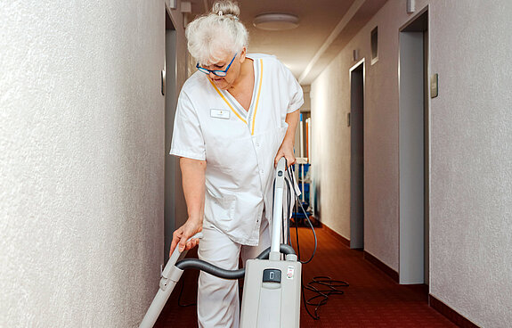 Petra Weber mit Staubsauger im Gang.