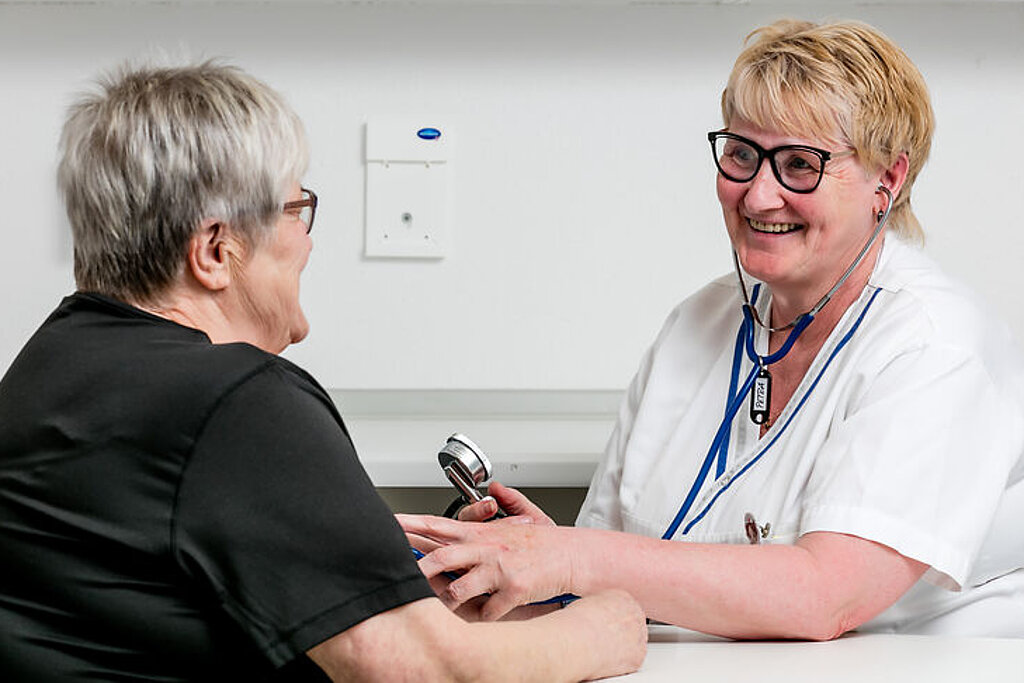 Eine Pflegekraft misst den Blutdruck einer Patientin.