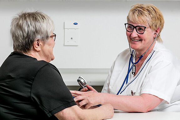 Eine Pflegekraft misst den Blutdruck einer Patientin.