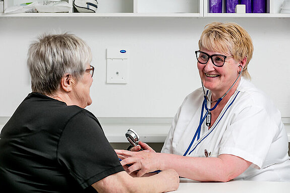 Eine Pflegekraft misst den Blutdruck einer Patientin.