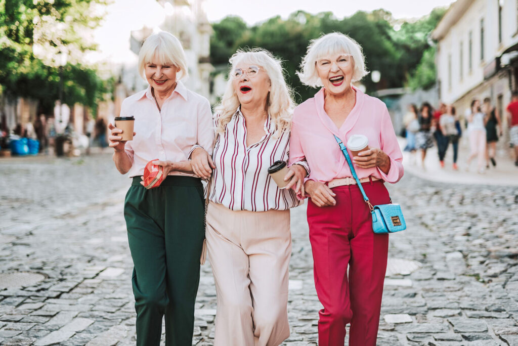 Drei ältere Damen in der Fußgängerzone lachend.